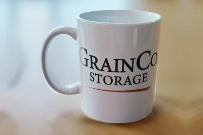 White mug printed with a company logo in black and a red line